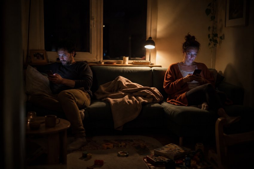 Ein Paar sitzt nebeneinander auf dem Sofa, jeder für sich am Handy