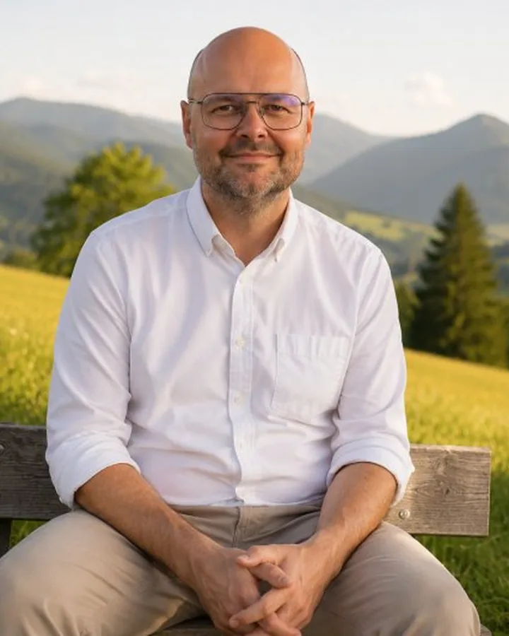 Christian, Mitgründer von Hier und Wir, auf einer Bank vor einer Berglandschaft